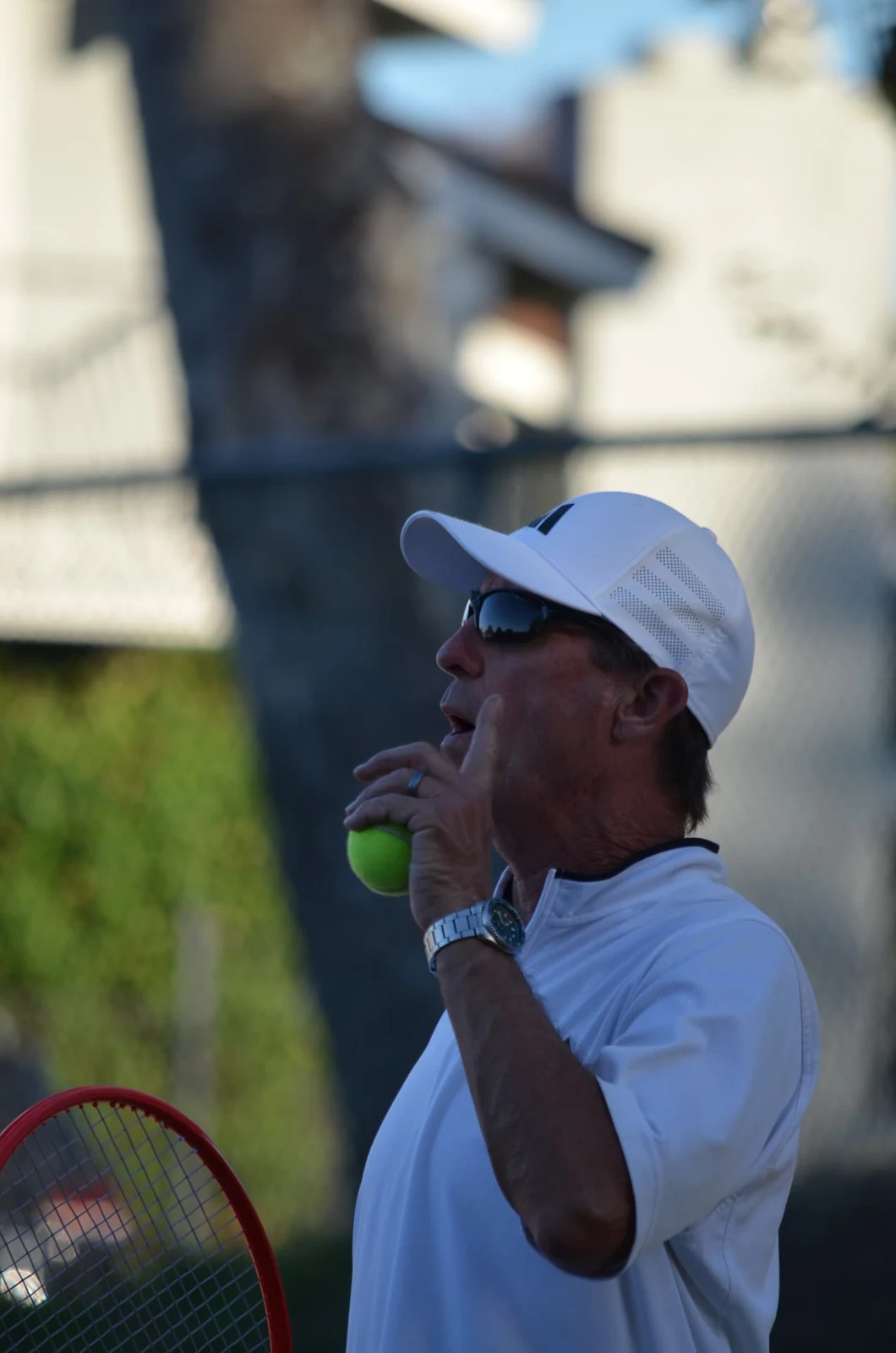 Coach Thor Schreck with a tennis ball and racket at Walnut Country Crossings