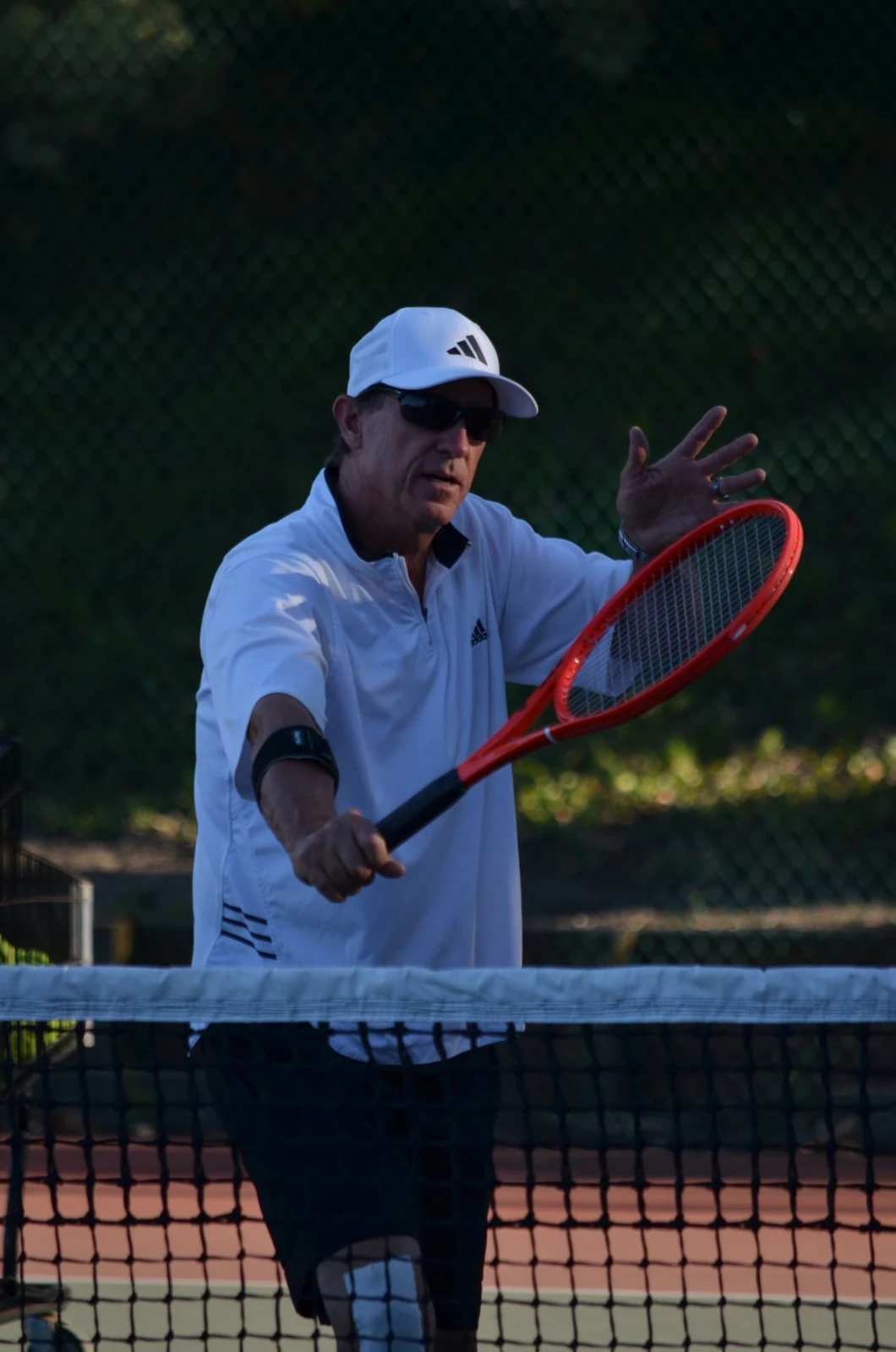 Coach Thor Schreck demonstrating racket technique on the tennis court